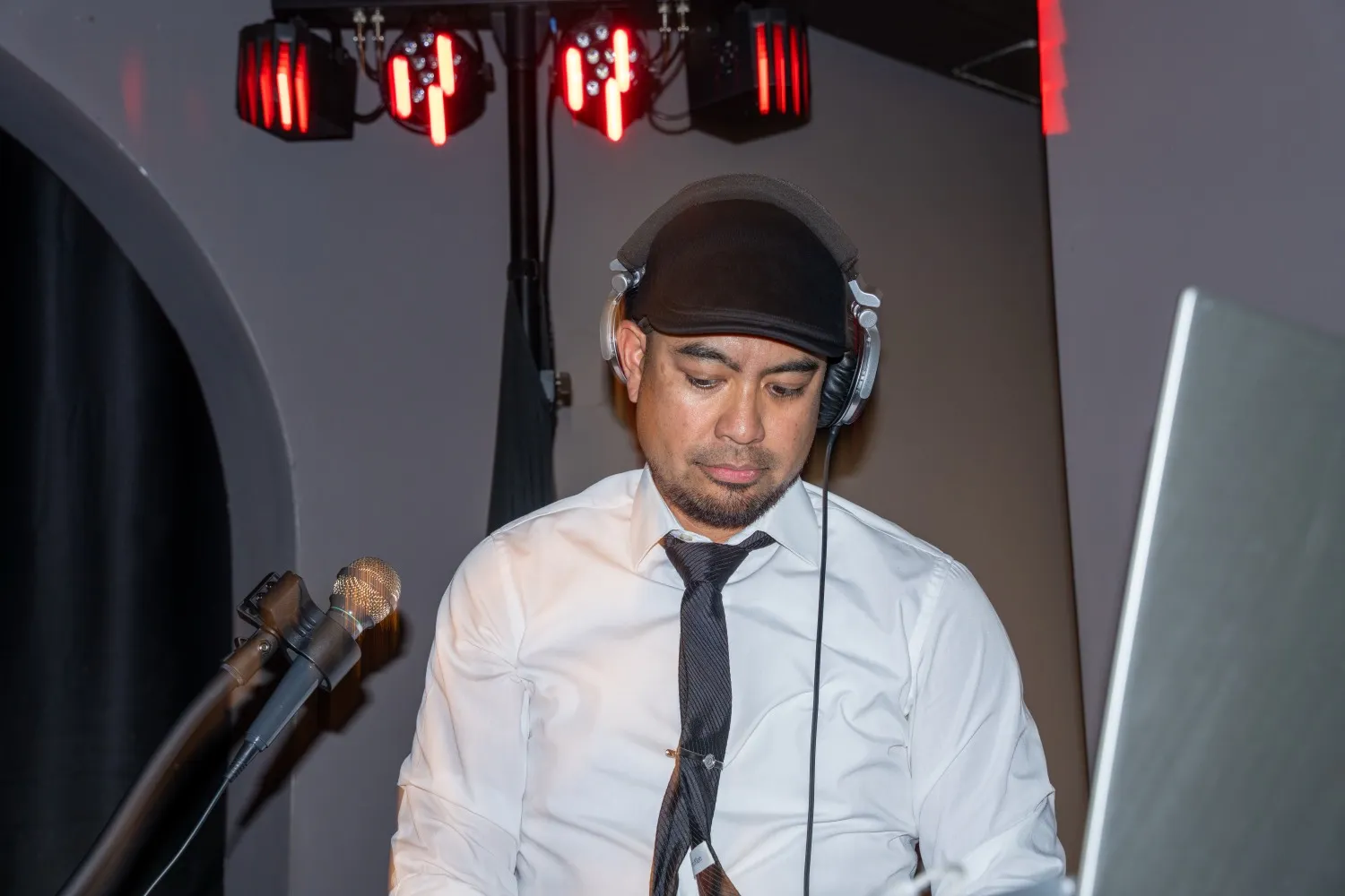 DJ in shirt and tie focused behind the decks at a formal event