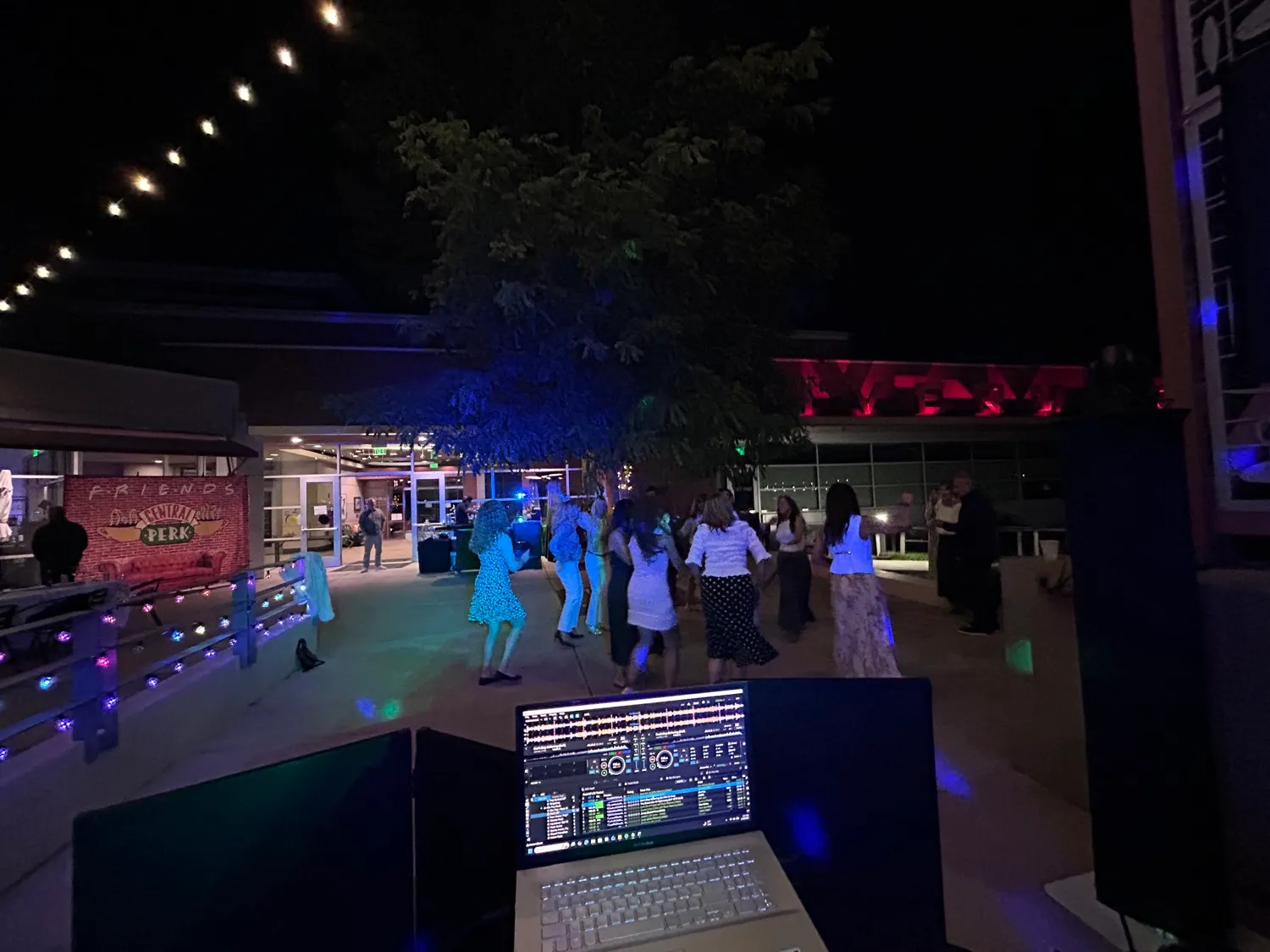 Guests dancing under string lights at an outdoor evening reception